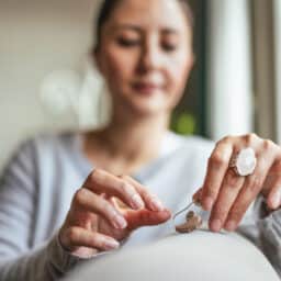 Young Adult Woman inserting battery into the Hearing Aid