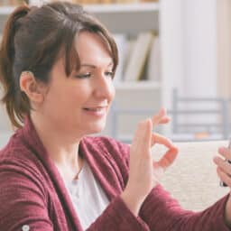 Woman with hearing aid using a smartphone.