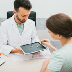 Audiologist helping a female patient choose a pair of hearing aids.