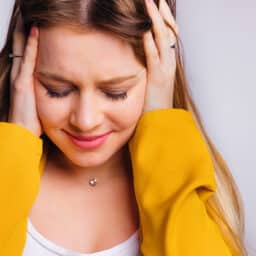 Woman with tinnitus holds ears