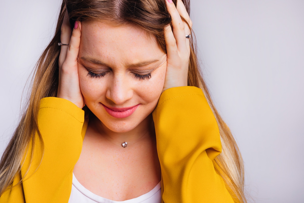 Woman with tinnitus holds ears 
