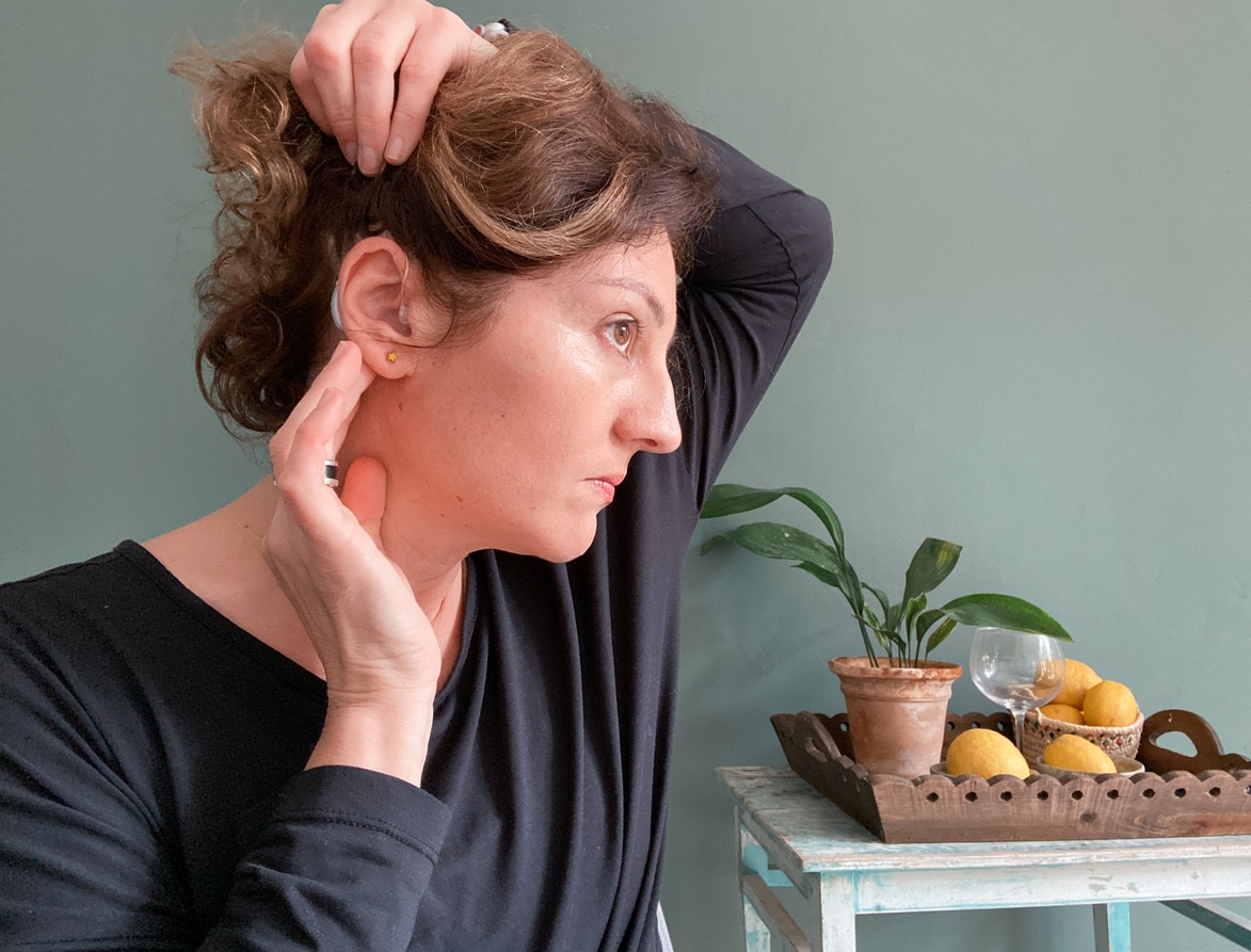 Woman looking at her hearing aid.