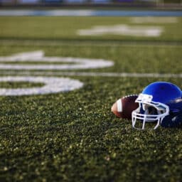 An American football helmet and football on the football field. Perfect image for your football announcement.